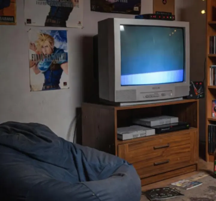 Nostalgiczny pokój gracza z epoki PlayStation, z konsolami PS1 i PS2 oraz półkami pełnymi gier